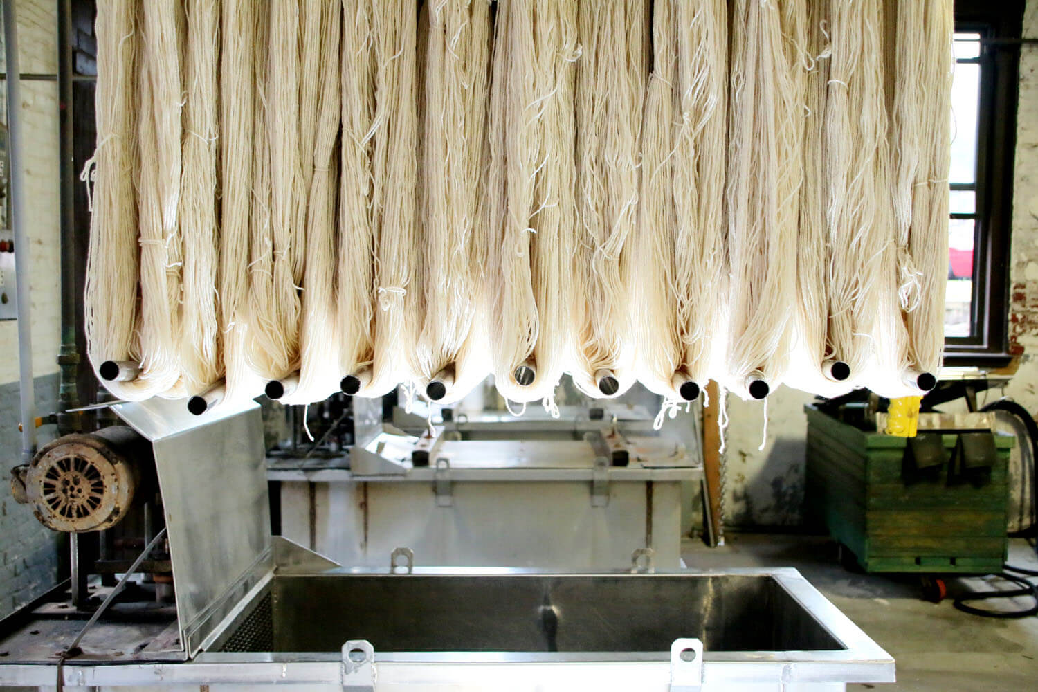 White fabric being hung from the ceiling of a textile mill during the fabric manufacturing process