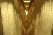 Bunches of white string fabric hanging in storage inside a textile facility
