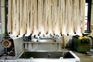 White fabric being hung from the ceiling of a textile mill during the fabric manufacturing process