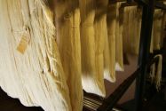Thick sections of tan fabric being hung together in a textile mill