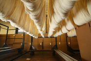Sections of white fabric hanging on a storage rack inside a textile mill
